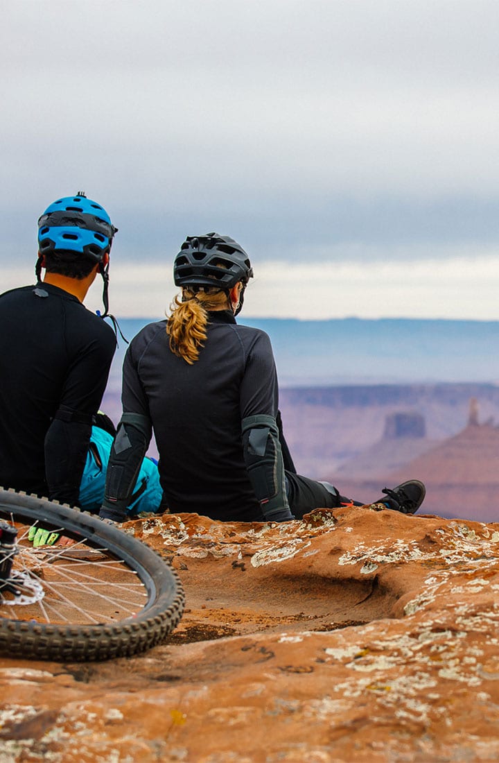 2 mountain bikers taking a break to sit and enjoy the scenery.